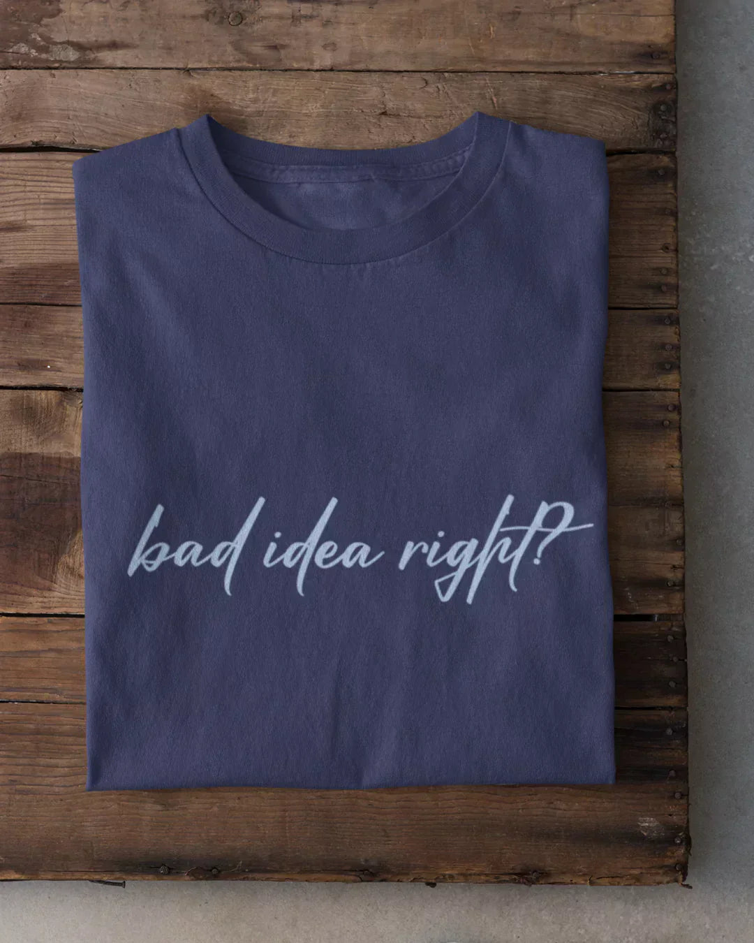 Bad Idea Right T-Shirt – navy regular tee with white script text, folded on a wood surface.