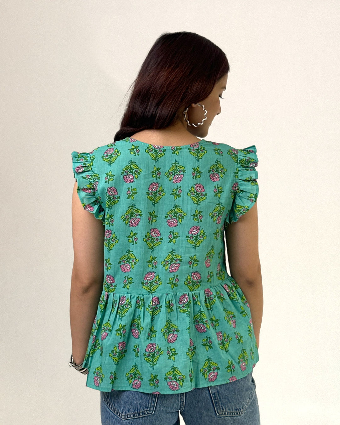 Green Cherry Peplum Top ā green floral print peplum top with ruffled sleeves, worn by model.