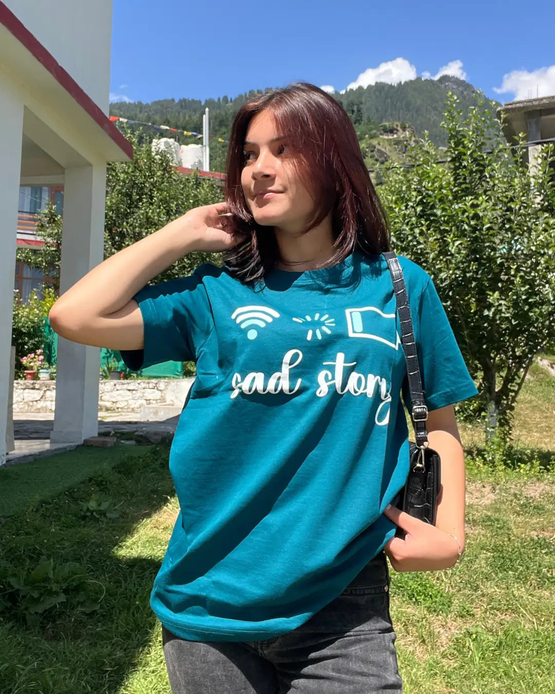 Loading T-Shirt – teal relaxed-fit regular tee with a white graphic and text, worn by a woman outdoors.