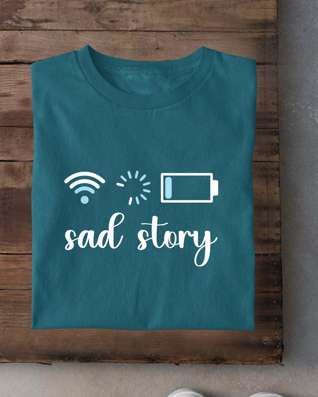 Loading T-Shirt – teal regular tee with a white 'sad story' graphic and icons