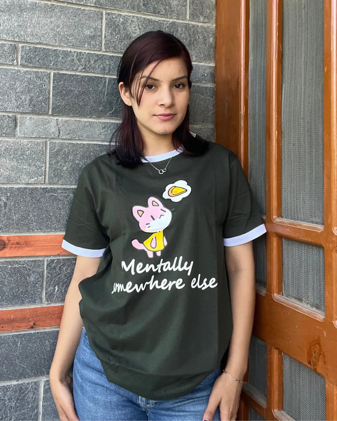 Mentally Somewhere Else Tap Out T-Shirt โ olive green relaxed tee with pink cat graphic and white text worn by model