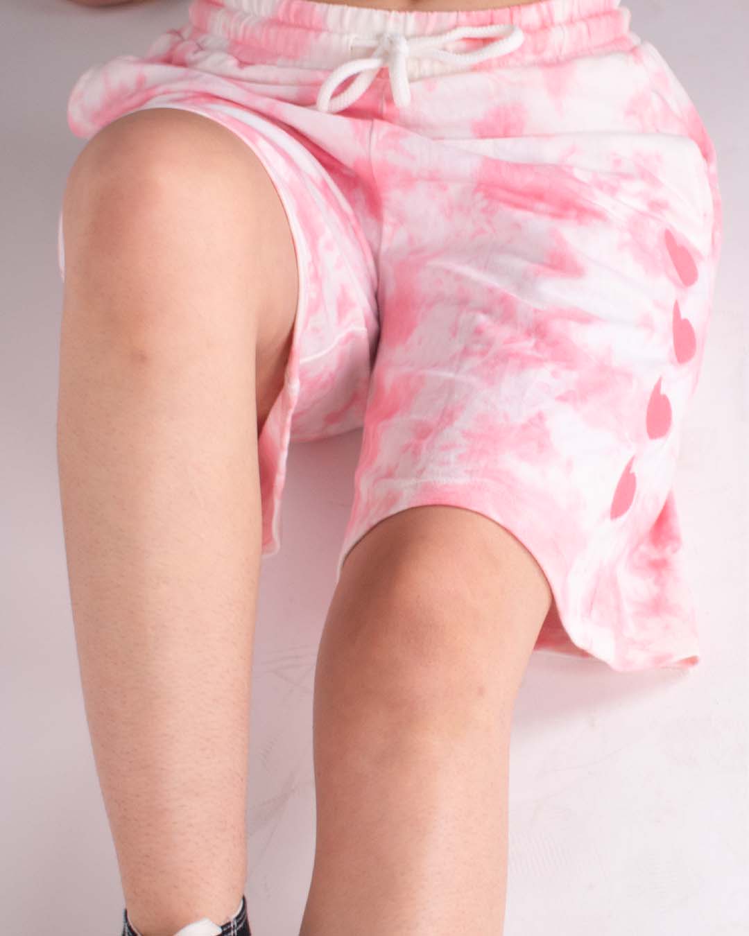 Pink Tie Dye Bermuda Shorts – pink and white tie-dye, relaxed-fit shorts with a white drawstring, worn by model