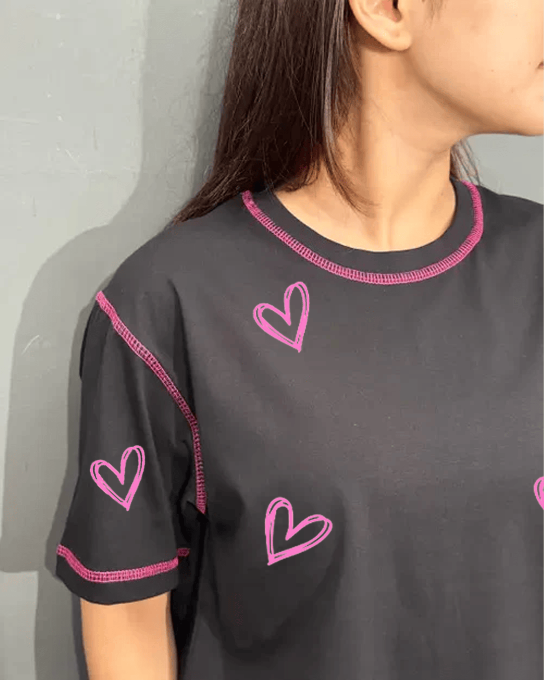 Reverse Weave Black Lover T-Shirt โ black regular tee with pink heart graphics and pink stitching, worn by model