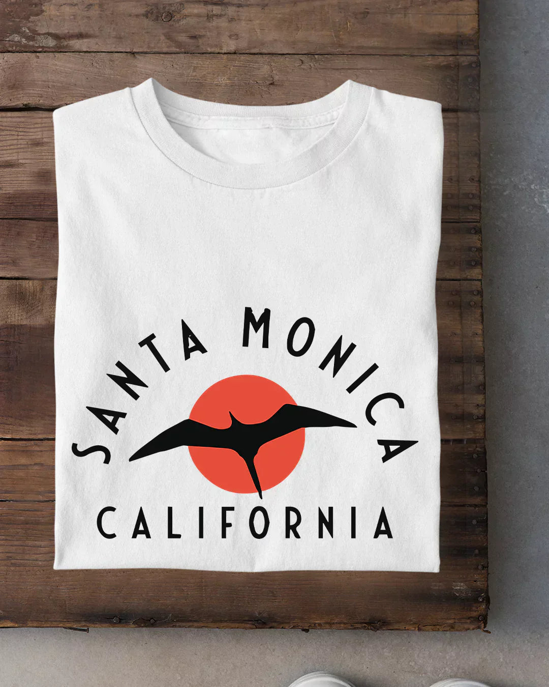 Santa Monica T-Shirt - white graphic tee with black seagull over orange sun and Santa Monica California text, flat lay