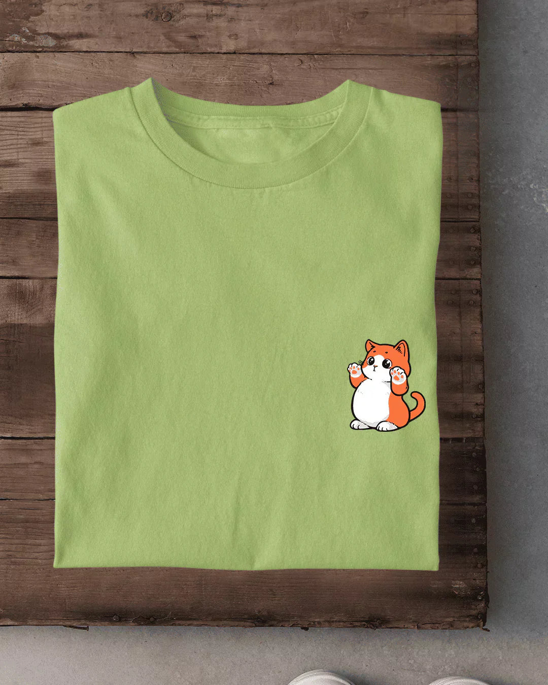 Standing Meow T-Shirt – lime green regular tee with an orange and white cat graphic on the front pocket, shown in flat lay
