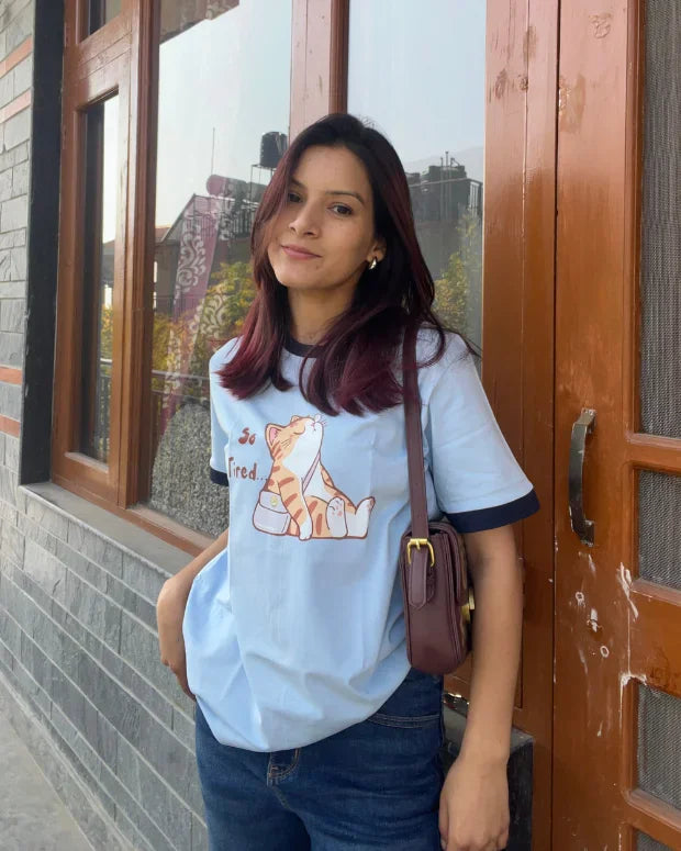 Tired Tap Out T-Shirt โ light blue regular tee with a cat graphic, worn by model