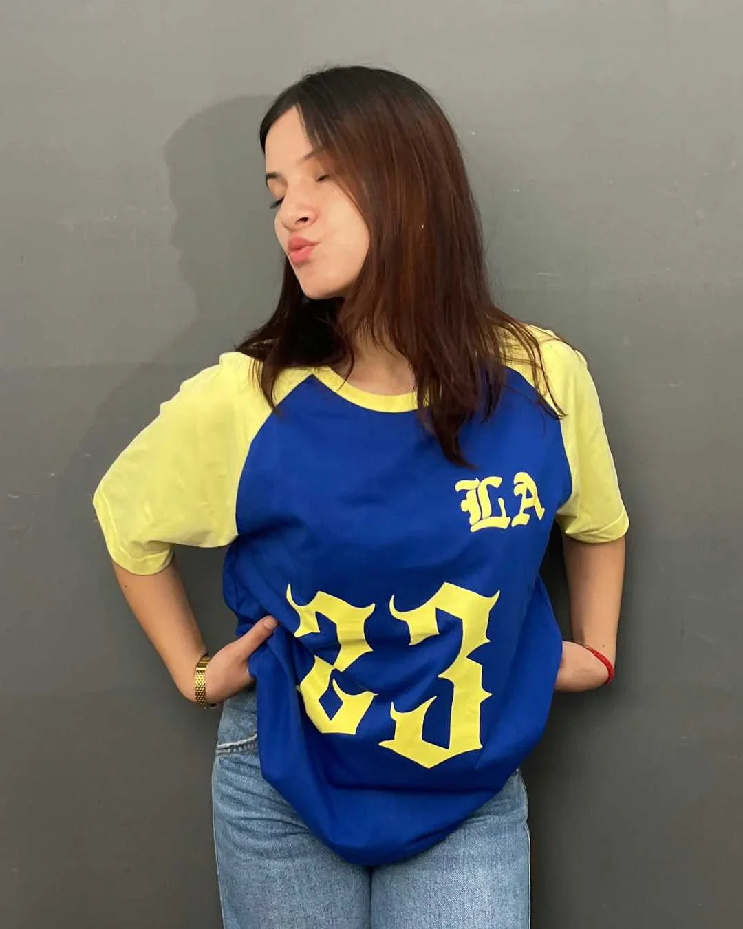23 LA Raglan Oversized T‑Shirt – blue body with yellow sleeves, large yellow 23 graphic and LA lettering, worn by model