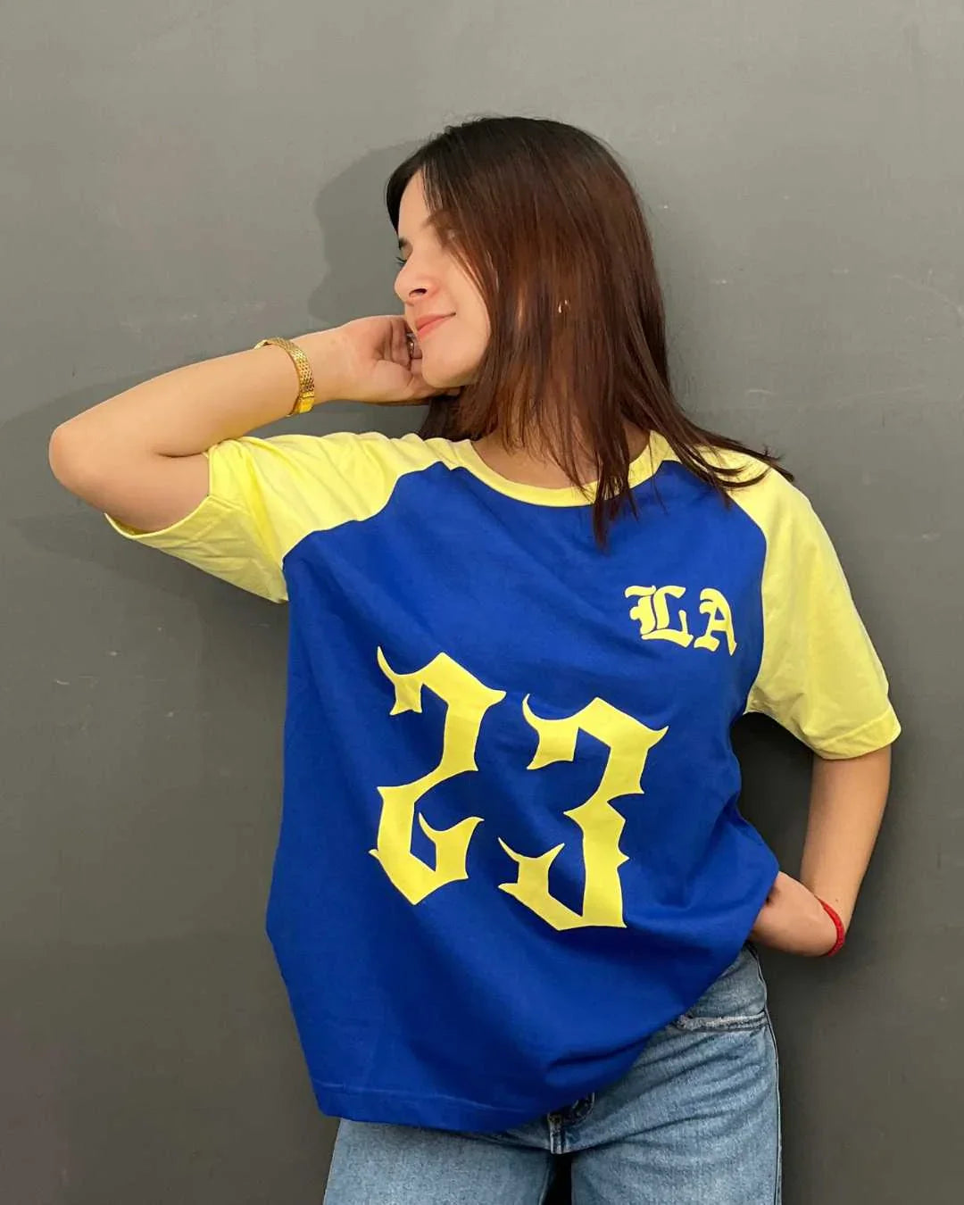 23 LA Raglan Oversized T-Shirt – blue body with yellow raglan sleeves, bold yellow 23 graphic and LA lettering, worn by model