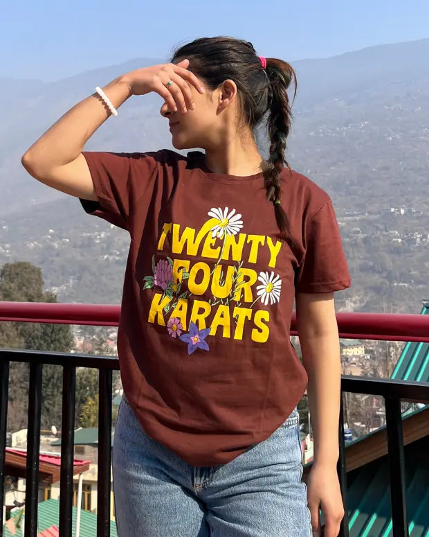 Beautiful scenary of mountains with a woman wearing a brown printed tshirt with the text Twenty Four Karats