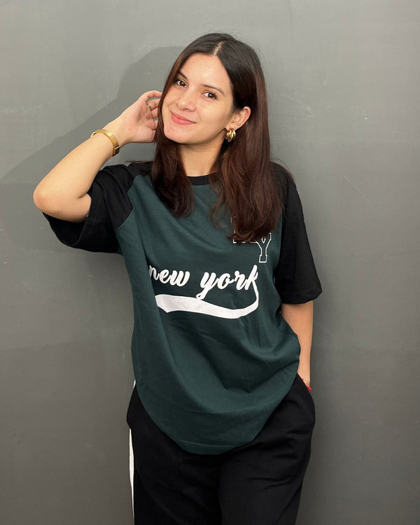 New York Raglan Oversized T-Shirt – dark green body with black raglan sleeves and white New York script graphic, worn by model