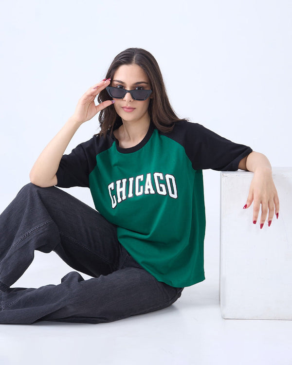 Chicago Raglan Oversize T-Shirt – green body with black raglan sleeves, oversized fit, CHICAGO print on front, worn by model