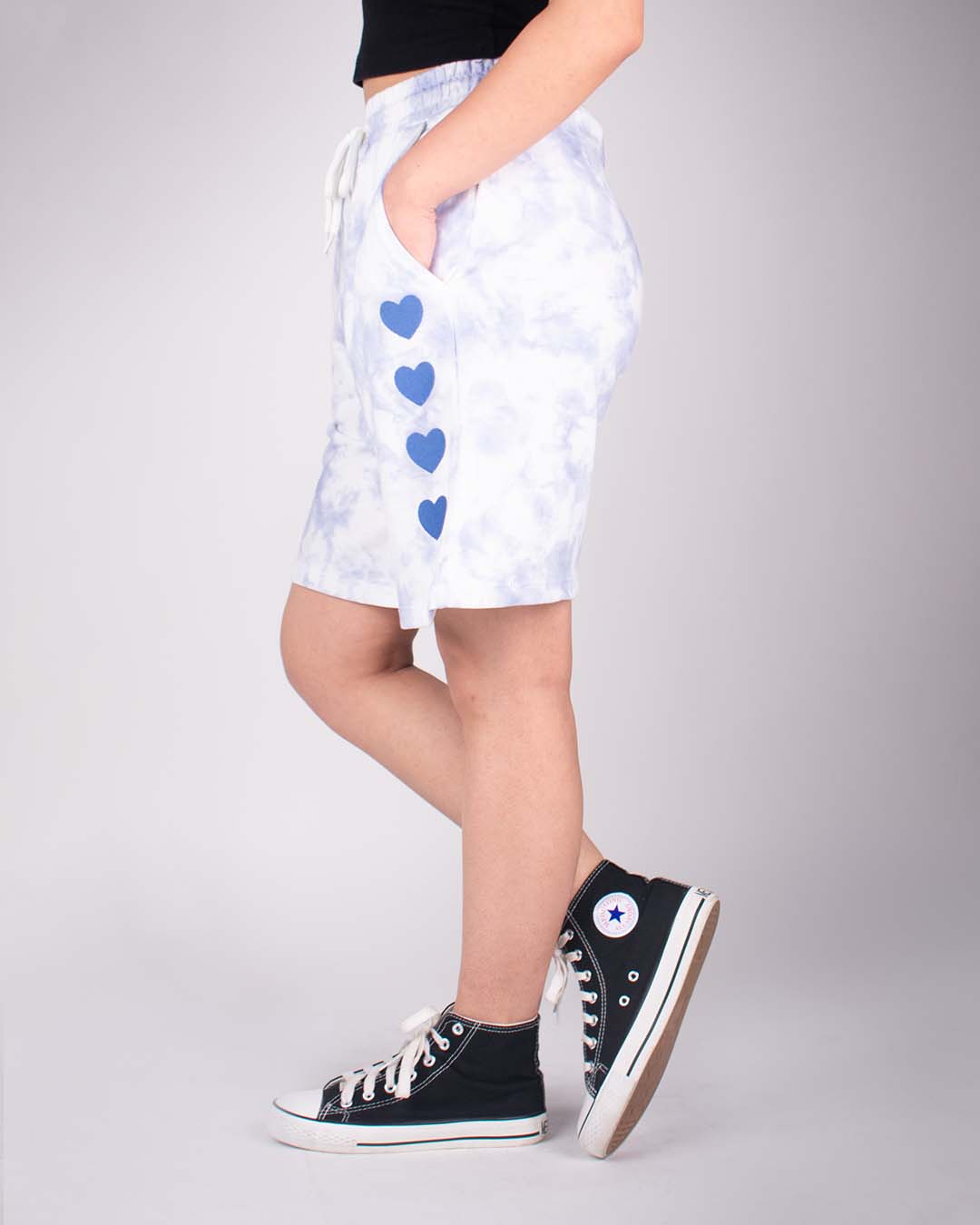 Blue Tie Dye Bermuda Shorts – relaxed-fit shorts with blue heart prints along the side, worn by model