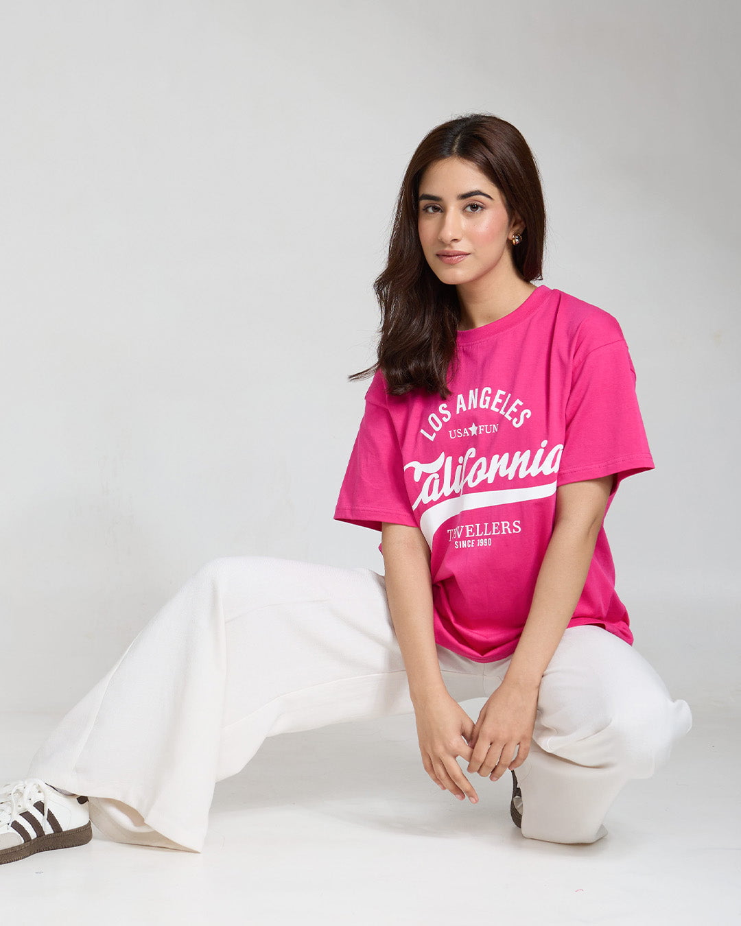California Travellers Oversized T-Shirt – pink graphic tee with California lettering, worn by model.