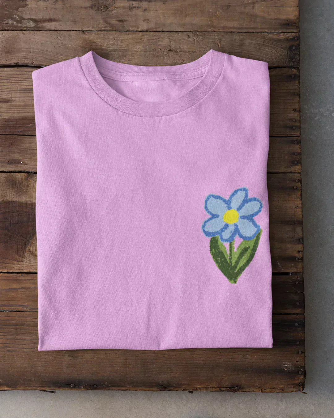 Crayon Flower T-Shirt – light pink tee with a blue flower graphic on the front lower-right.