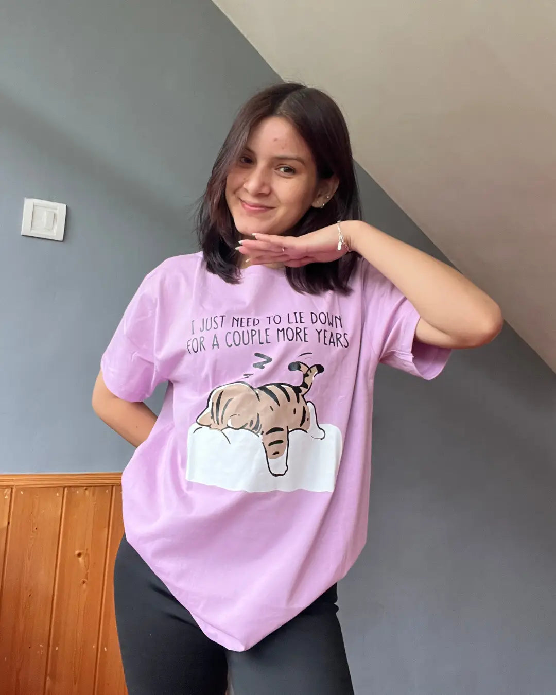 I Just Need To Lie Down T-Shirt – lavender relaxed-fit Regular Tee Graphic with a tiger resting on a white bed, worn by model