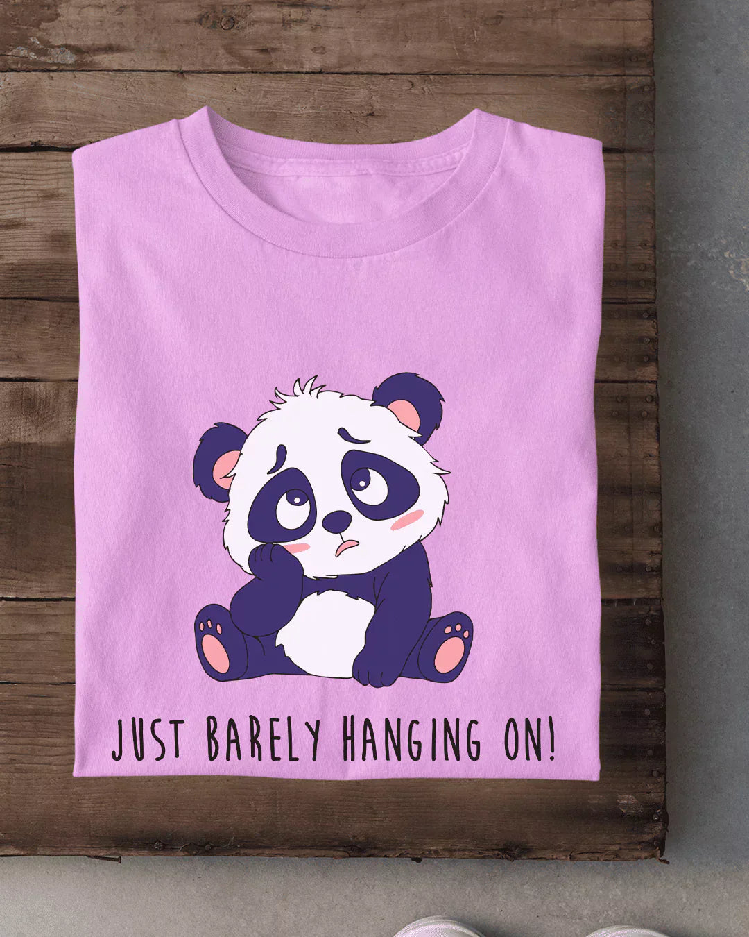Just Barely Hanging On T-Shirt – pink regular tee with a panda illustration, shown in flat lay