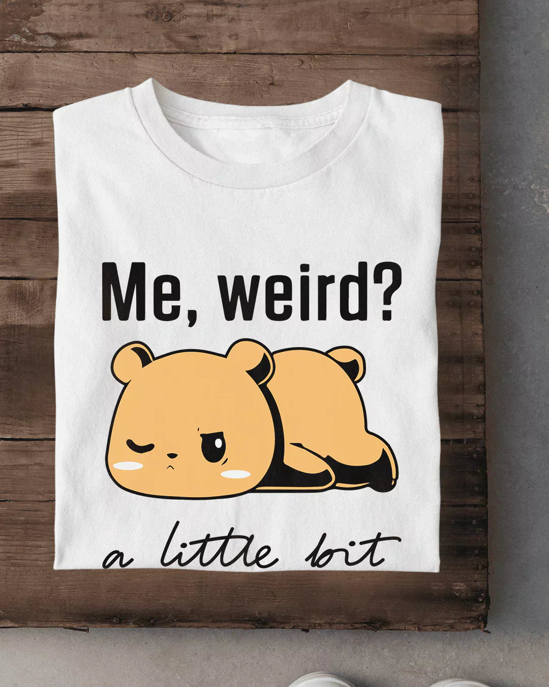 Me Weird T-Shirt – white regular tee with a beige cartoon bear graphic and Me, weird? text, shown flat on wood