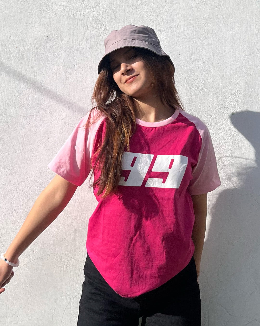 Pink 99 Raglan T-Shirt – pink body with lighter pink raglan sleeves and a white 99 logo across the chest, worn by model