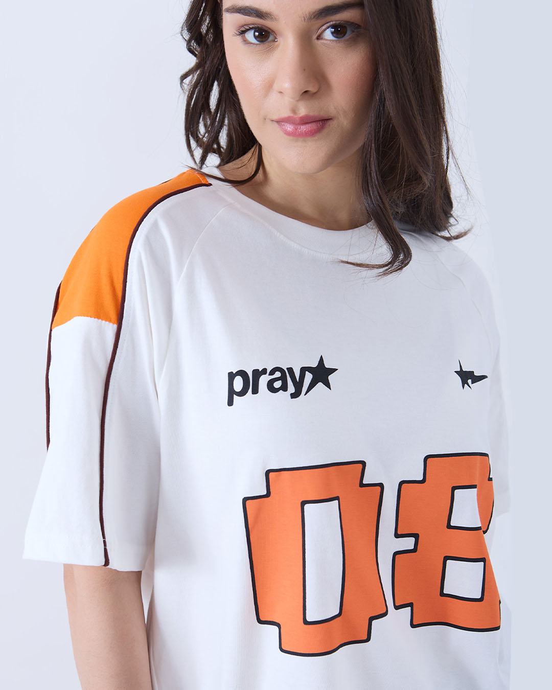 Pray Downtown Oversize T-Shirt – white raglan tee with orange graphic across chest and black Pray logo, worn by model