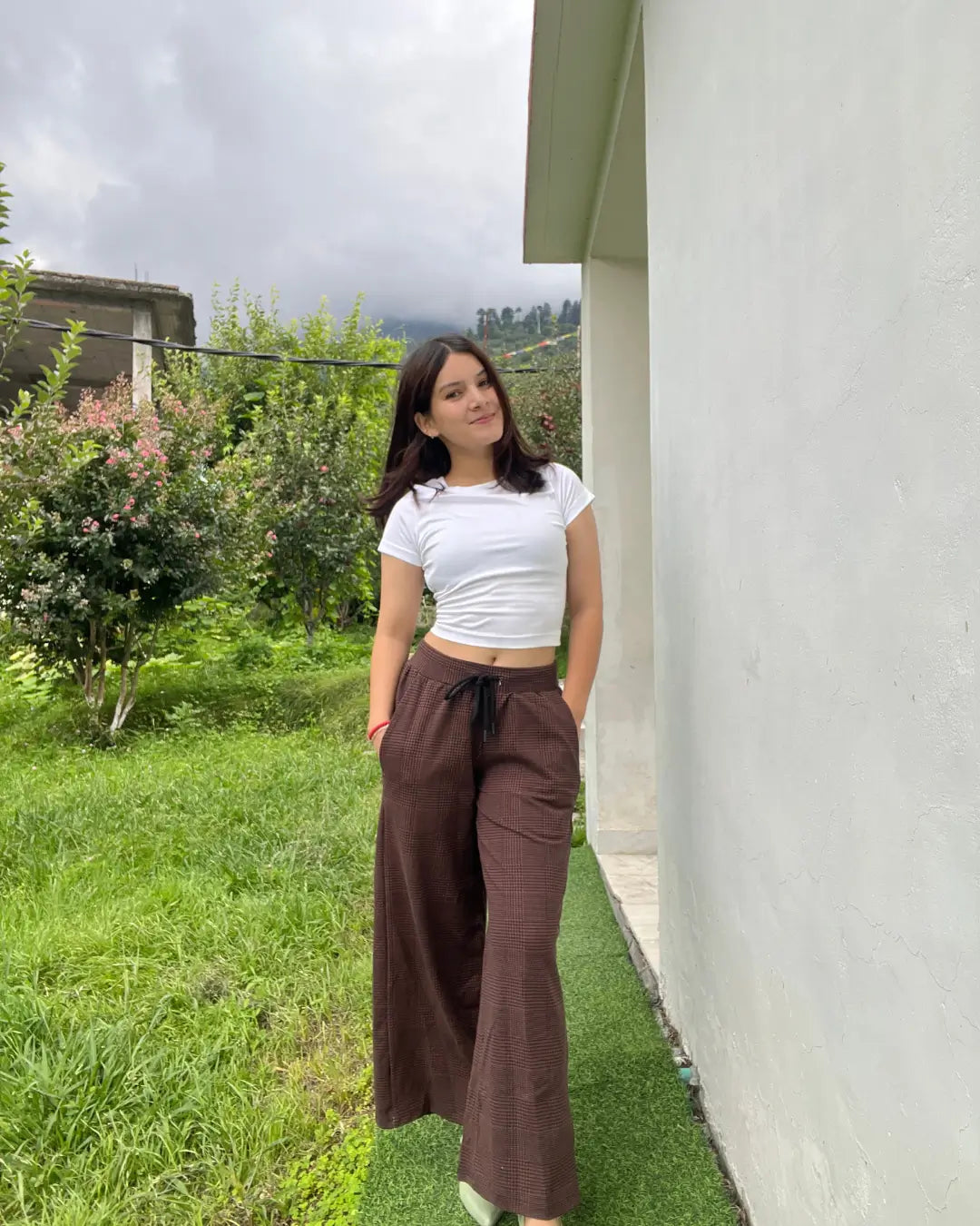 Rustic Pajama – brown plaid wide-leg pajama pants with a black drawstring, paired with a white cropped tee, worn by model.
