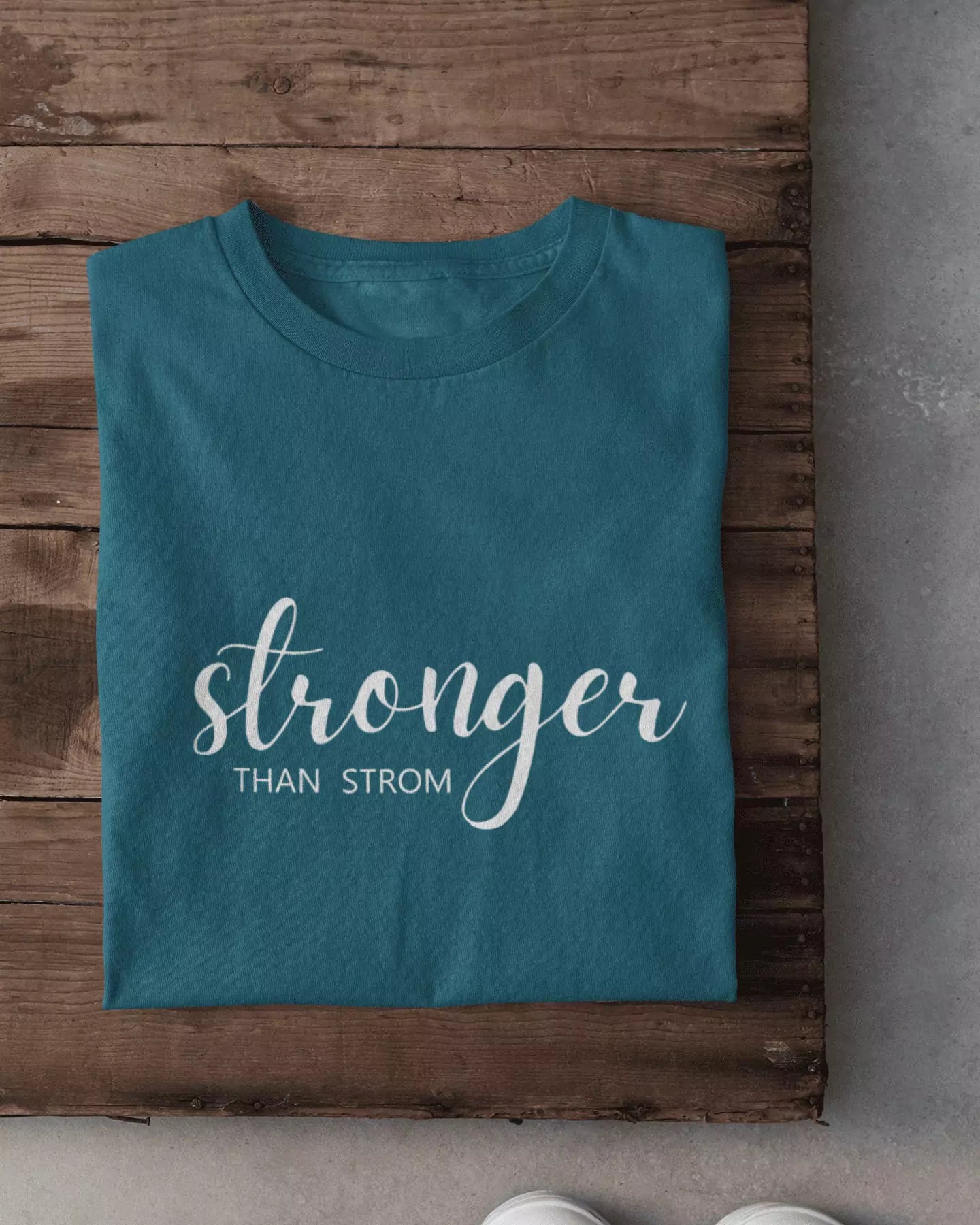 Stronger Than Strom T-Shirt – teal regular tee with white script graphic on front, shown in flat lay