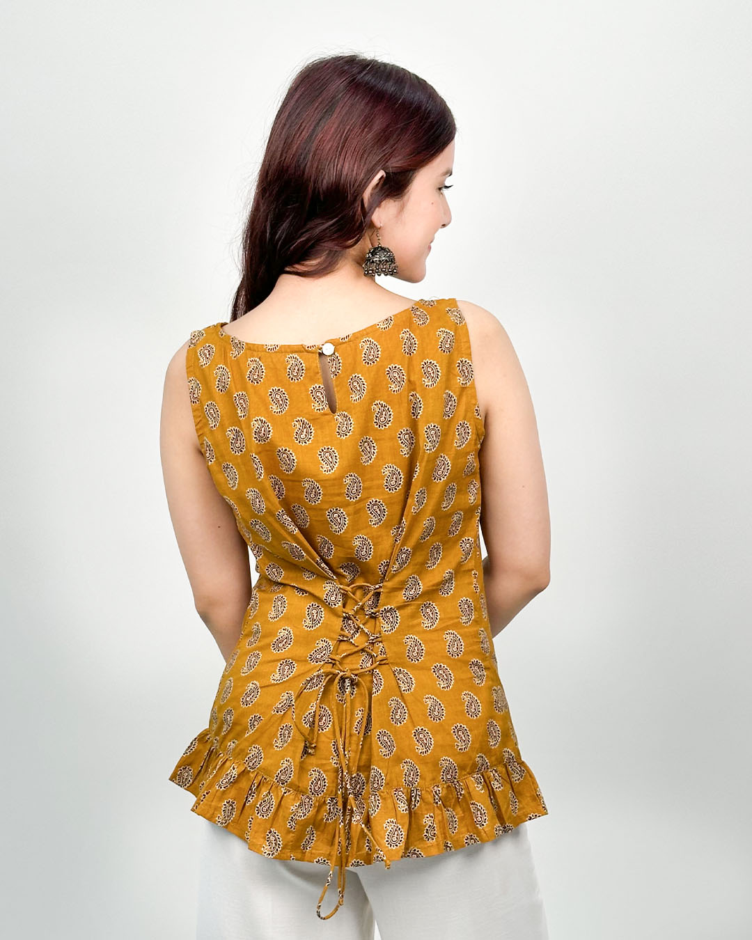 Yellow Sunehri Snatched Short Kurti mustard yellow printed sleeveless kurti with back lace and ruffled hem, worn by model.